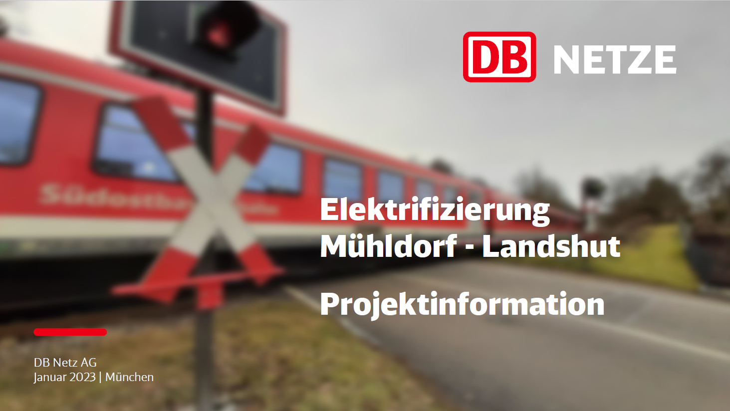Ein roter Dieselzug überquert einen Bahnübergang hinter dem Andreaskreuz